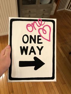 a person holding up a one way sign on the floor in front of a door