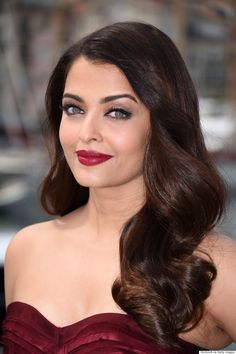 an image of a woman with long dark hair and red lipstick on her face wearing a strapless dress