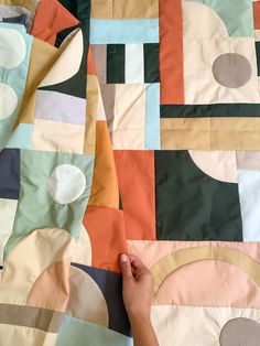 someone is making a quilt with different colored squares and circles on it's surface