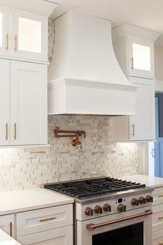 a stove top oven sitting inside of a kitchen next to white cabinets and counter tops