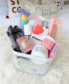 a white basket filled with lots of beauty products on top of a bed next to pillows