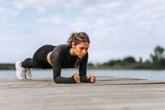 a woman is doing push ups on a dock