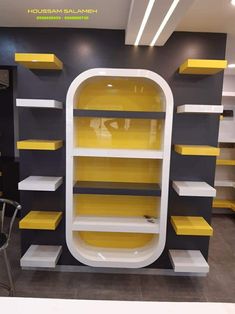 yellow and grey shelves in a store with chairs around them, all painted black and white