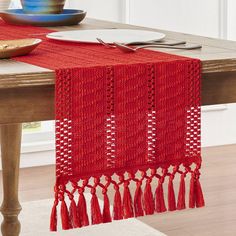 a red table runner with tassels on it