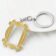 a white plate with a silver and gold frame keychain sitting on top of it