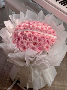 a large bouquet of pink roses sitting on top of a white box next to a piano