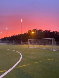 a soccer field with a goal and lights at sunset