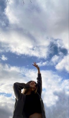 a woman is flying a kite in the sky with her hands up to catch it