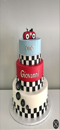 a three tiered cake decorated with cars and checkered paper on the bottom layer