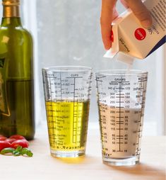 a person pouring dressing into two glasses