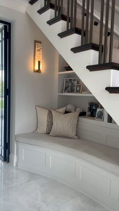 a white bench sitting under a staircase next to a window