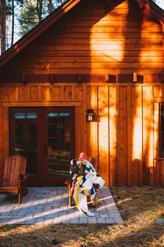 a woman sitting on a bench in front of a wooden cabin