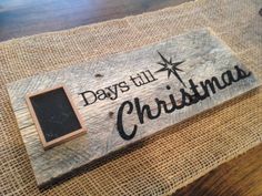 a sign that says days till christmas on the side of a wooden table with burlap