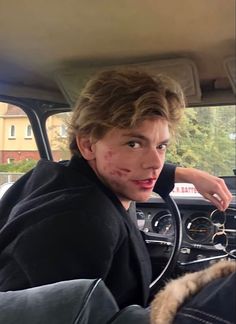 a young man sitting in the driver's seat of a car