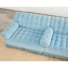 a blue couch sitting on top of a floor next to a white wall and carpet