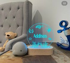 a teddy bear sitting on a chair next to a personalized acrylic sign