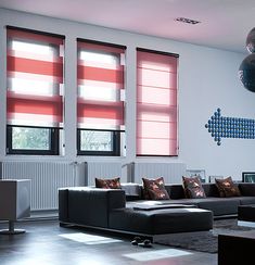 a living room filled with furniture and windows covered in red roller shade shades on the windows