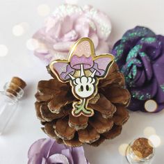 a pine cone with a minnie mouse pin sitting on top of it next to some flowers