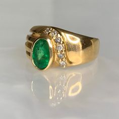 An unusual and delightful vintage solid 14k gold ring featuring a glowing oval shaped emerald weighing 0.80 carats accented by sparkling white diamonds weighing 0.11 carats. *Natural inclusions are present and are an indication that the stone is genuine. *Ring size: 6 1/4 * Ring weight: 5.65 grams *Complimentary resizing is available up to 3 sizes larger or smaller than stated size. Oval Emerald Ring Fine Jewelry Collectible, Green Oval Diamond Ring Collectible, Classic Oval Emerald Collectible Ring, Classic Oval Emerald Ring Collector's Item, Heirloom Oval Emerald Ring Collectible, Collectible Heirloom Oval Emerald Ring, Oval Art Deco Emerald Ring Stamped 14k, Emerald Gold Jewelry, Dainty Earrings Studs