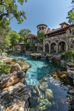 a large house sitting on top of a lush green hillside next to a river filled with water