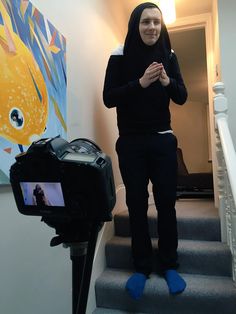 a woman is standing on the stairs in front of a camera