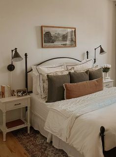 a bedroom with a bed, nightstands and pictures hanging on the wall above it