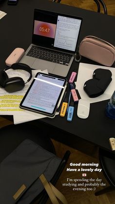 a laptop computer sitting on top of a desk next to a phone and headphones