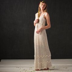 a woman in a long dress standing on a white floor with flowers around her head