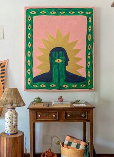 a painting hangs on the wall next to a table with baskets and other items in front of it