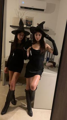 two women dressed up in witches hats and boots, posing for the camera with their hands on their hipss