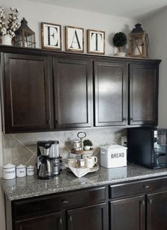 a kitchen with dark wood cabinets and white counter tops, coffee maker on the side