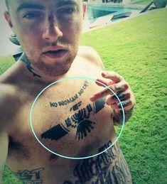 a man with tattoos on his chest holding a magnifying glass in front of him