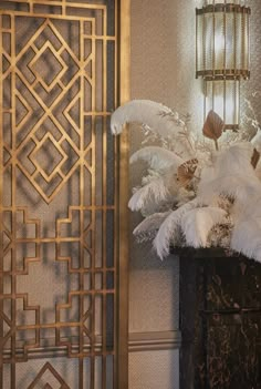 a vase filled with white feathers next to a decorative wall hanging on the side of a building