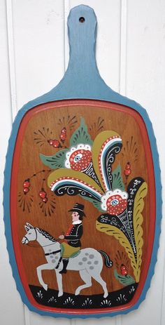 a wooden plaque with an image of a man riding a horse on it's side