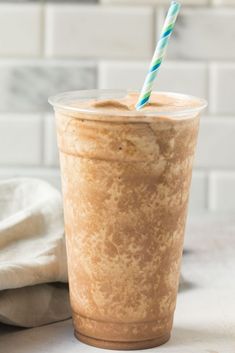 a cup with a straw in it sitting on a counter top next to a towel