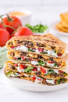 two quesadillas stacked on top of each other with tomatoes and lettuce