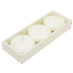 three white candles in a box on a white background