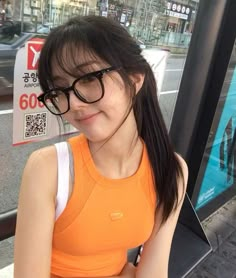 a woman in an orange shirt and black glasses