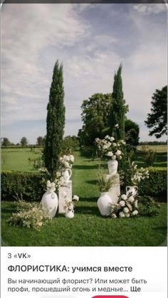 two white vases sitting in the middle of a lush green field