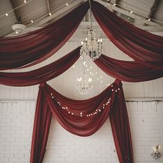 a room with red drapes and chandelier hanging from the ceiling