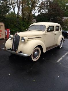 an old white car parked in a parking lot