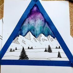 a piece of paper that has been made to look like a triangle with mountains in the background