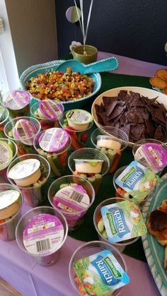 a table topped with lots of food on top of a purple cloth covered tablecloth