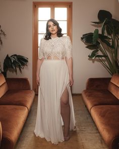 a woman standing in a living room wearing a white dress with sheer lace on it