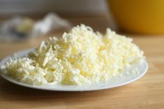 a white plate topped with shredded cheese on top of a wooden table