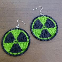 a pair of green and black beaded earrings on top of a wooden table next to each other