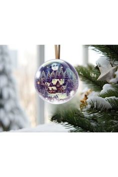 a christmas ornament hanging from a tree in front of a window with snow on the ground