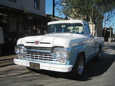 an old white truck is parked on the street