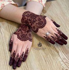 two hands with henna tattoos on them sitting on a wooden table next to each other