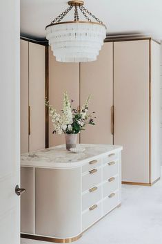 a vase with flowers sitting on top of a white counter in a room filled with closets